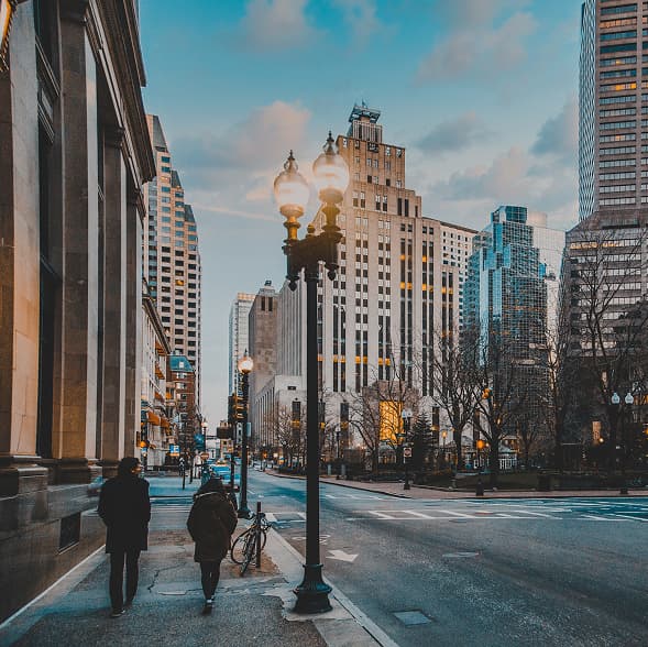 Ciudad con personas y faroles al atardecer
